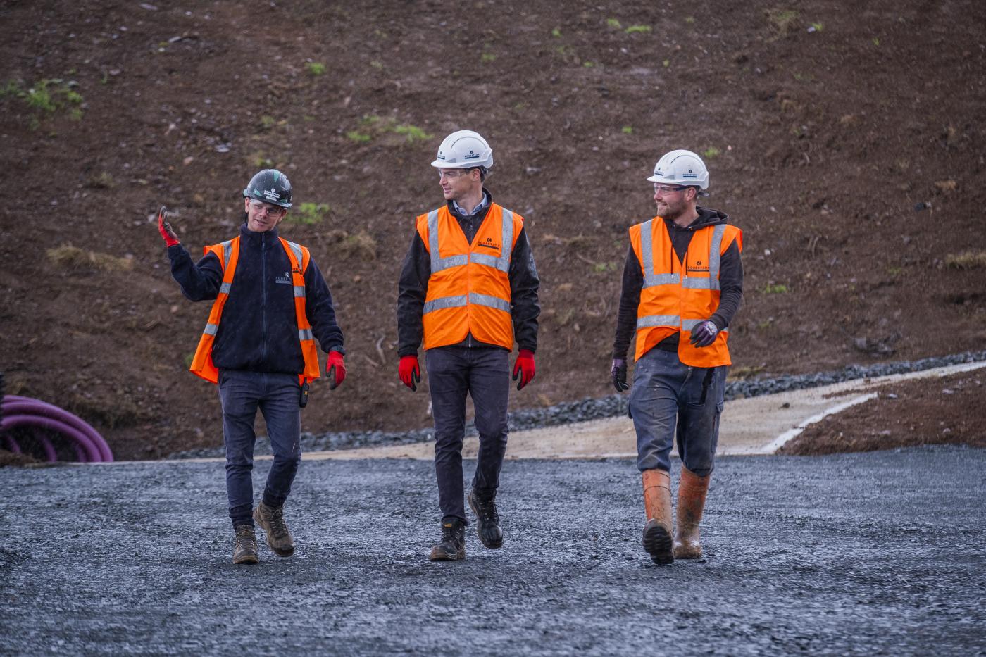 Three members of Robertson Civil Engineering walking towards the camera on the Hillend Snowsports Centre site in Edinburgh.