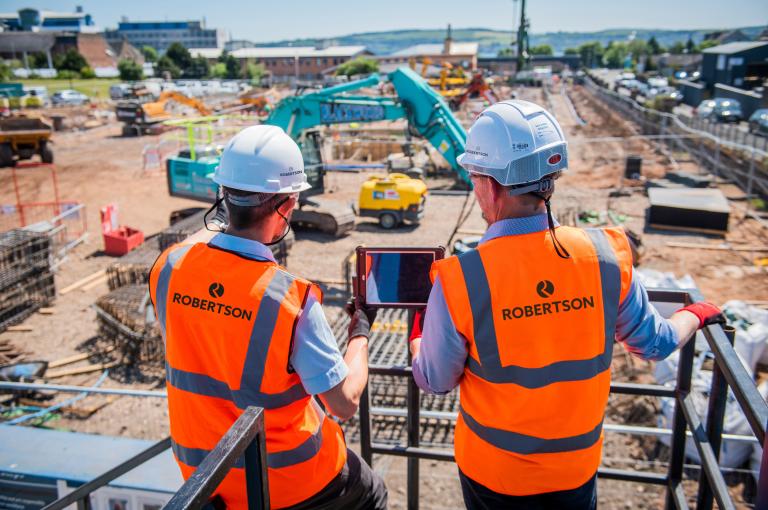 Two people wearing PPE looking across a construction site