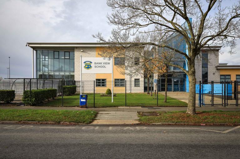 External image of a school with fence field and gate in foreground