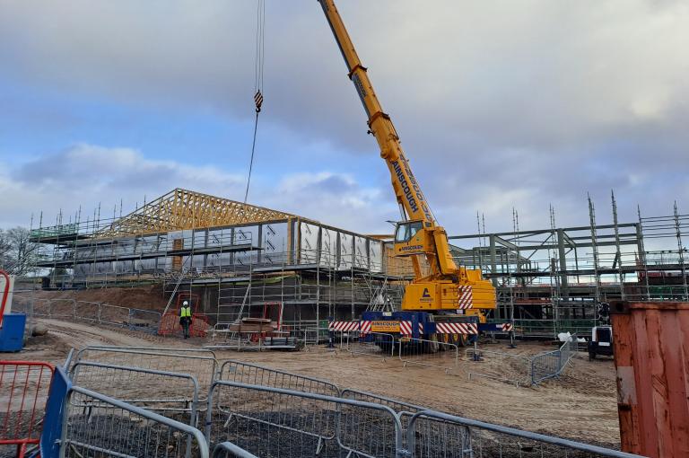 Commercial building under construction with timber and timber roof being craned into place