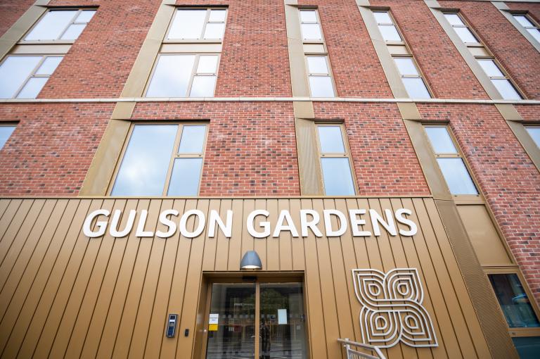 The exterior of the building which displays a large white sign that reads "Gulson Gardens".