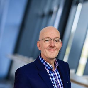 Headshot of businessman in coloured check open neck shirt