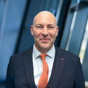 headshot of a business executive in blue suit and red tie