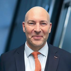 headshot of a business executive in blue suit and red tie