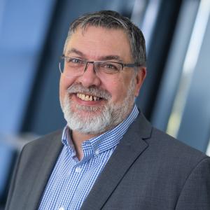 Businessman in grey suit and blue striped shirt with glasses and grey beard