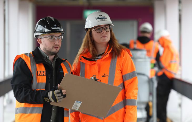 A male and female member of Team Robertson on site, wearing PPE. The man is holding a clip board.