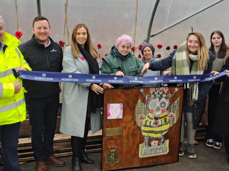 Row of people cutting a ribbon with wooden lectern in centre