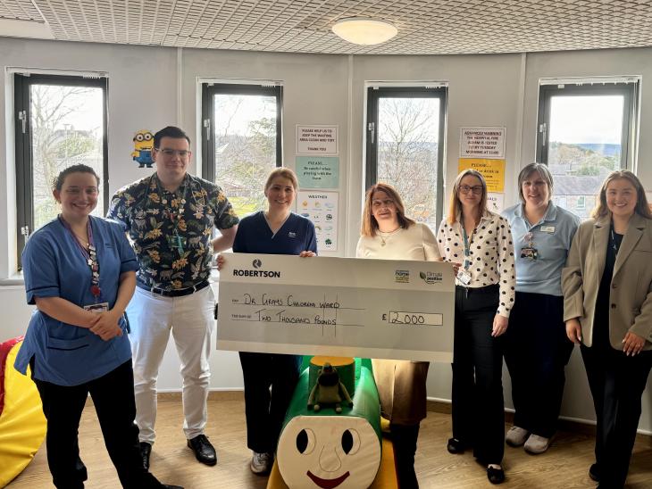 Representative from Robertson Property presenting the Children's Ward at Dr Gray's Hospital in Elgin a cheque for £2,000, surrounded by nurses and employees among children's toys