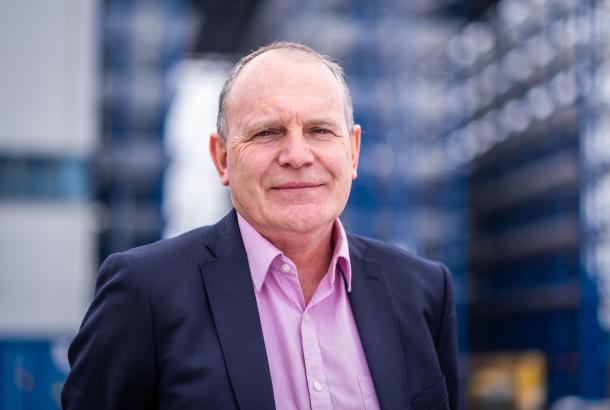 Robertson's Business Development Director, David Mackenzie, wearing a dark blue suit and pink shirt, looking at the camera and smiling.