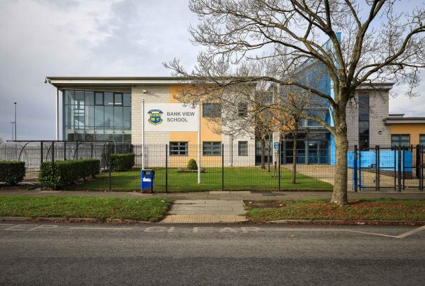 External image of a school with fence field and gate in foreground