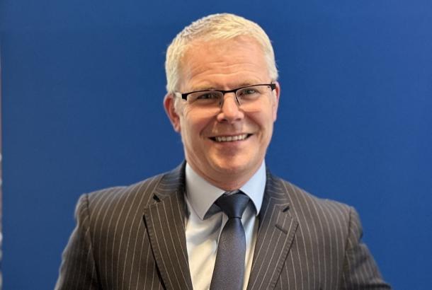 Gary Bushnell, Managing Director, Robertson Capital Projects, standing in a pinstripe black suit leaning on a banister