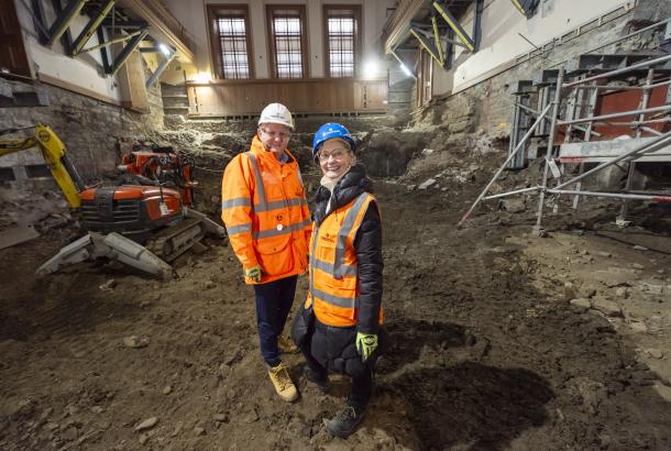 Two people in PPE, one from Robertson Construction and the other from Royal High School Preservation Trust, standing in the grand hall of the National Centre for Music to announce the project commencing.