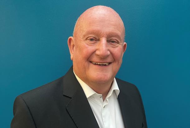 Headshot of businessman in black suit and white open neck shirt