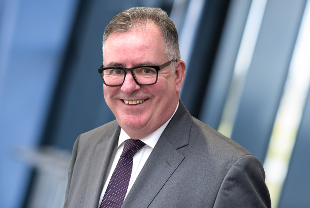 Headshot of Graham Hutcheon, a Non Executive Director Robertson Group, waring grey suit