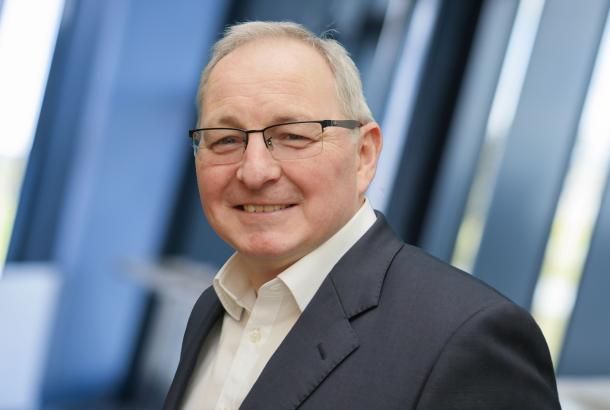 Headshot of male senior business leader in dark blue suit and white shirt