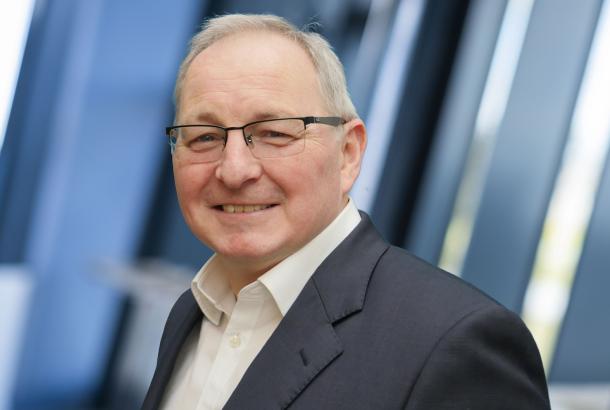 Headshot of male senior business leader in dark blue suit and white shirt
