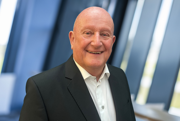 Headshot of businessman in black suit and white open neck shirt