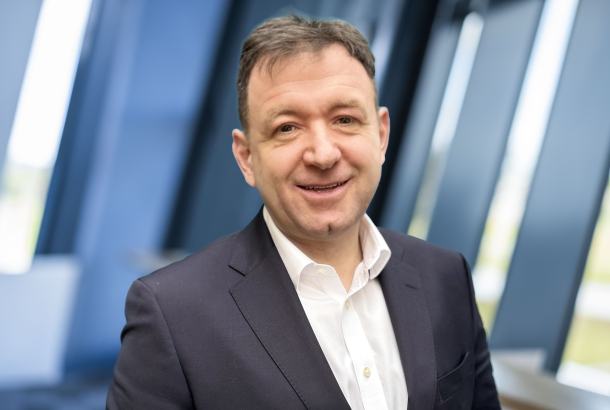 headshot of a business executive in white shirt and blue jacket