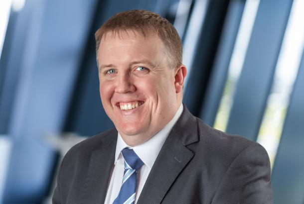 Headshot of businessman in grey suit white shirt and blue striped tie