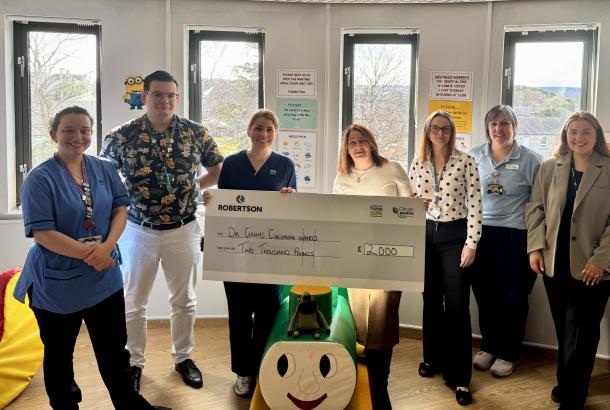 Representative from Robertson Property presenting the Children's Ward at Dr Gray's Hospital in Elgin a cheque for £2,000, surrounded by nurses and employees among children's toys