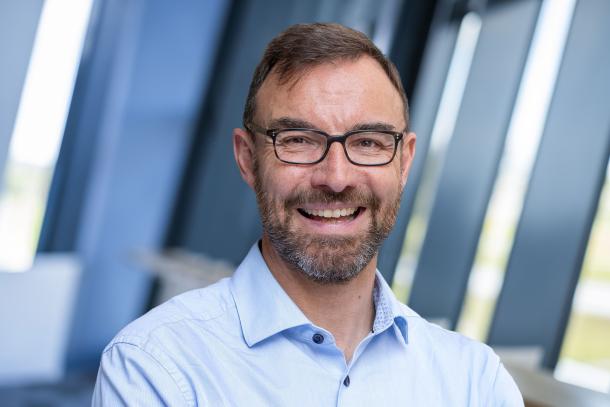 headshot of a business executive in blue open neck shirt