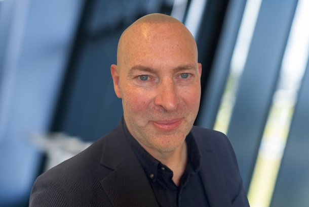 headshot of businessman in black suit and black shirt