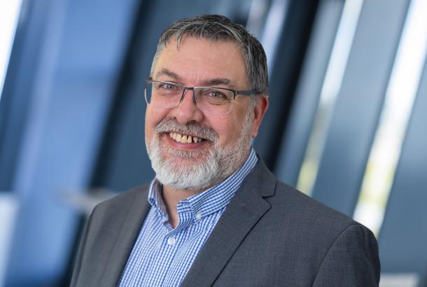 Businessman in grey suit and blue striped shirt with glasses and grey beard