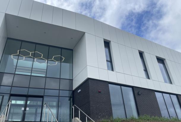 Image of outside of new college building upper half white lower half dark grey with glass entrance