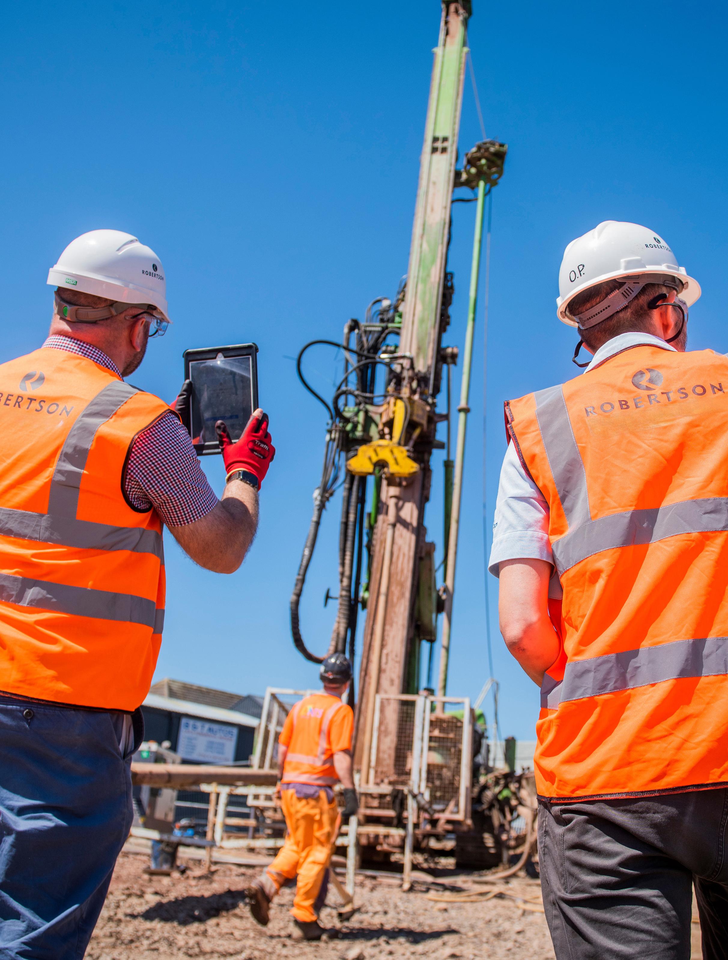 Two Robertson employees looking out onto a construction site photographing construction activity