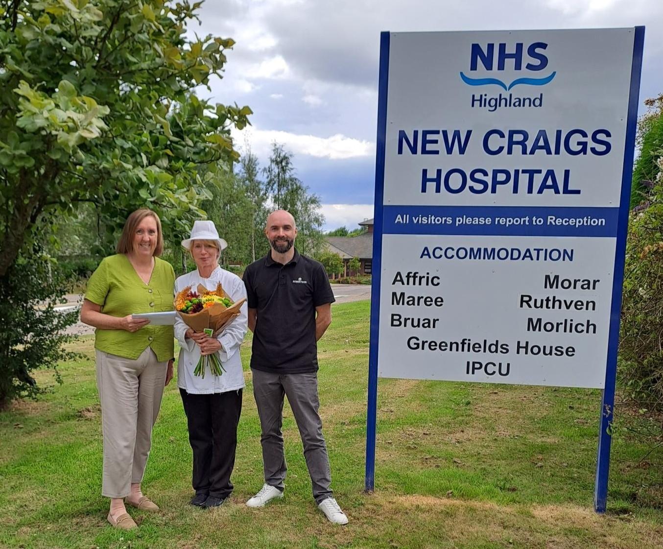 Three people next to NHS New Craigs Hospital sign