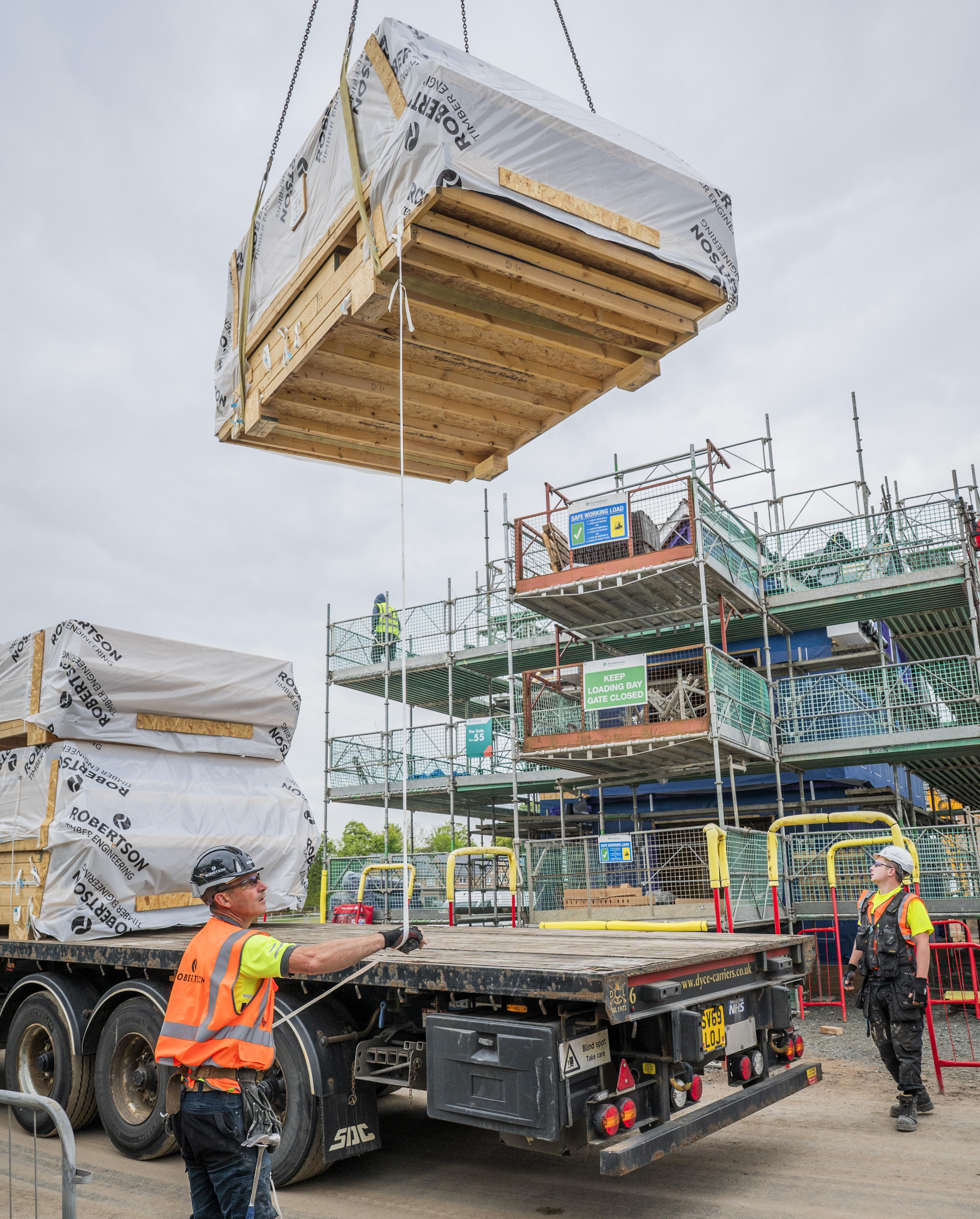 Timber frame panels being craned into place on a construction site