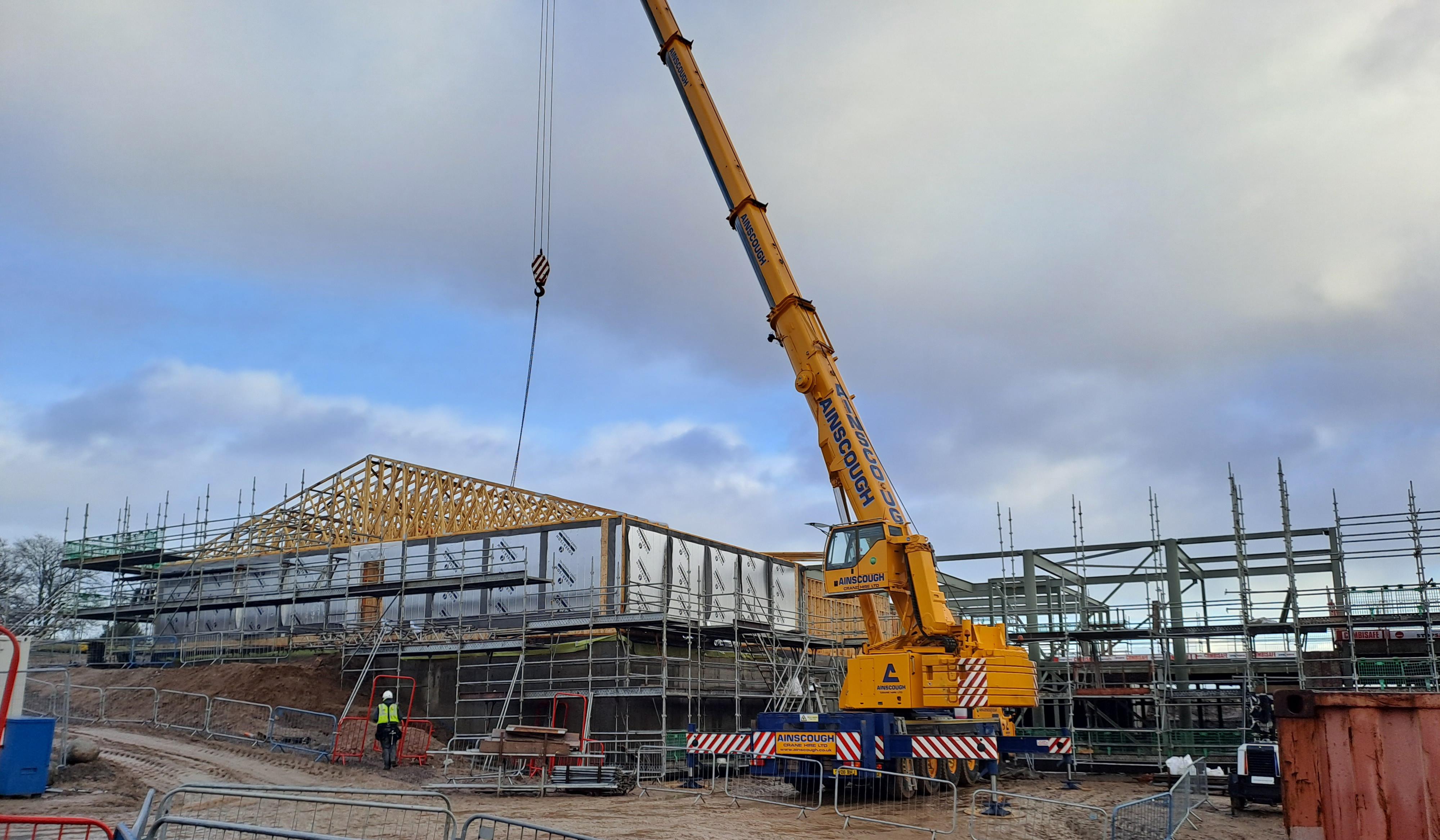 Commercial building under construction with timber and timber roof being craned into place