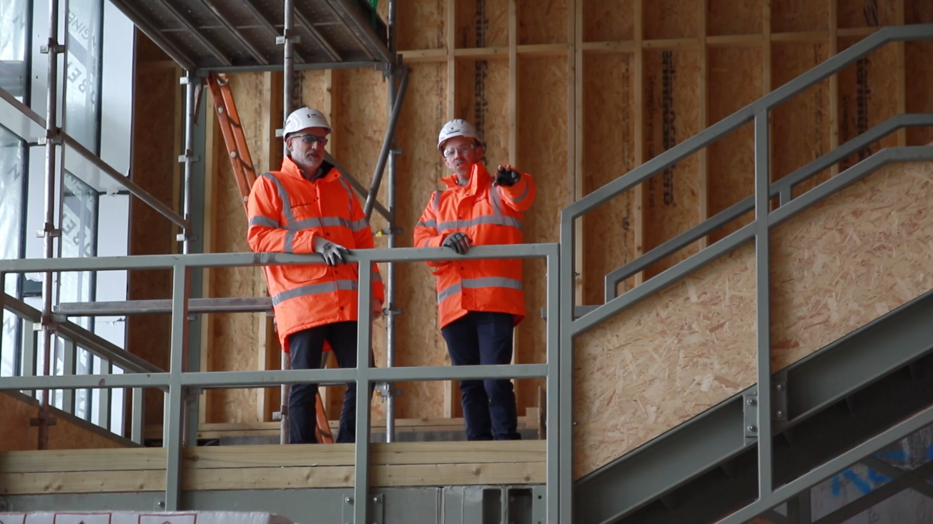 Commercial building under construction with timber frame and workers in safety clothing