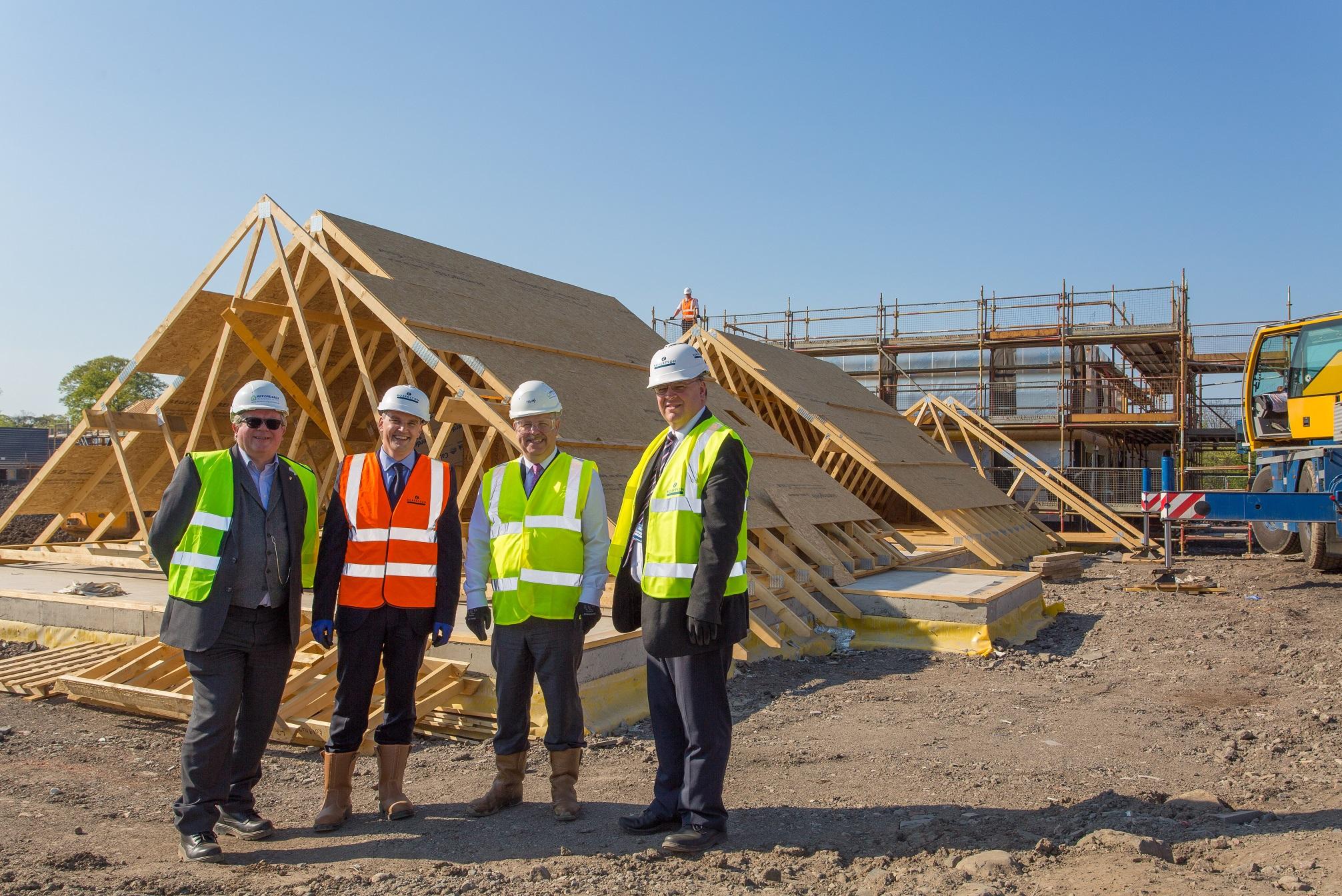 Image of men on construction site in front of timber frame construction in progress
