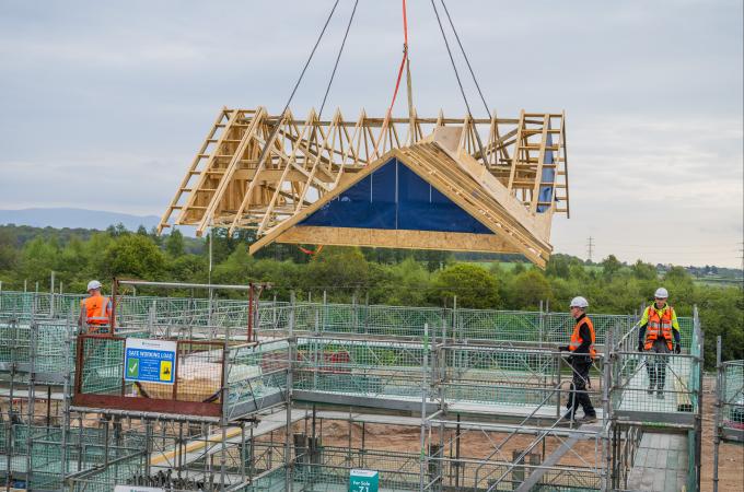 Timber frame roof manufactured off site being craned into place