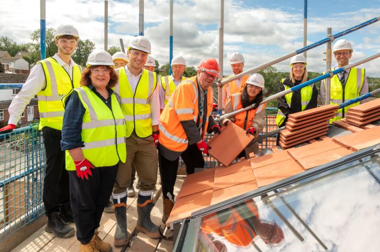 Kirklees Council laying a roof tile to mark the milestone with the project team