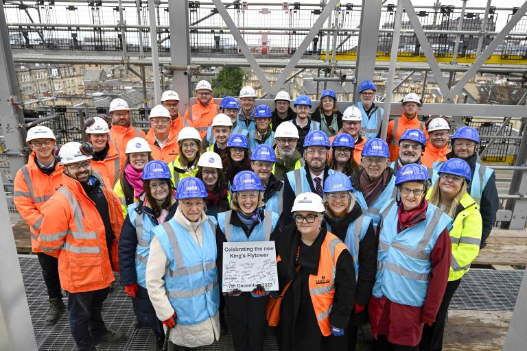 Steel signing event at Edinburgh King's Theatre, where Robertson Construction Central East are delivering a transformation of the Edwardian building for Capital Theatres. Guests showcasing the signed plaque on the roof.