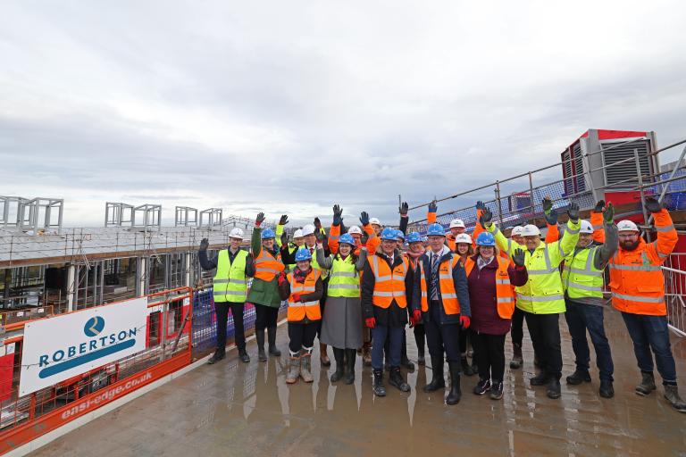 Councillors, guests and Robertson Construction North West cheering to celebrate a construction milestone at Mynydd Isa Campus