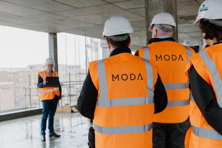 Man presenting to people wearing personal protective equipment at a construction topping out event