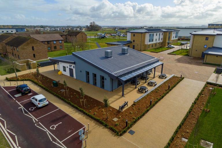 Aerial picture of accommodation hub with EV car park at RAF Lossiemouth with blue sky