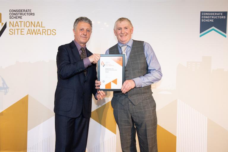 Two people holding an award certificate