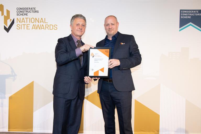 Two people holding an award certificate