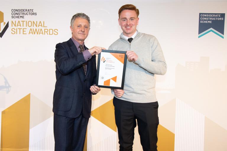 Two people holding an award certificate