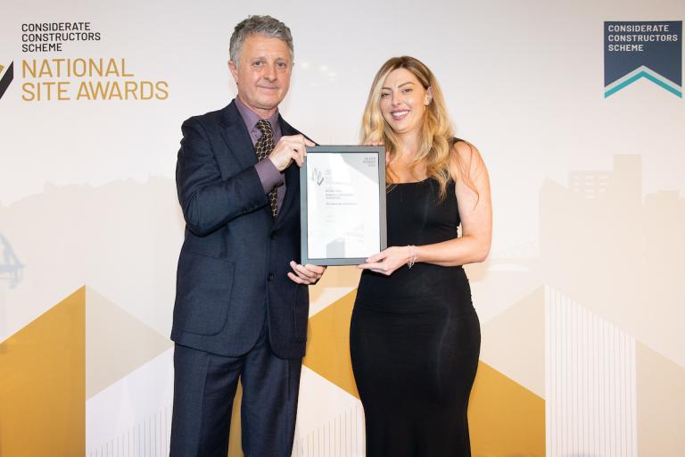 Two people holding an award certificate
