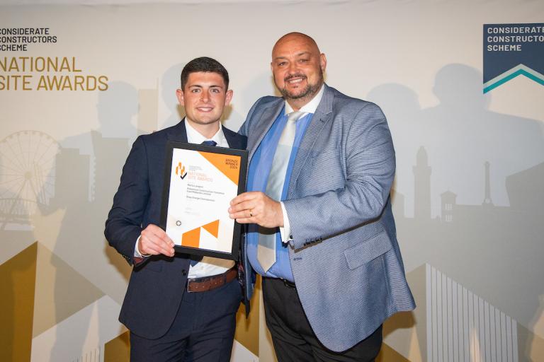 Two people holding an award certificate