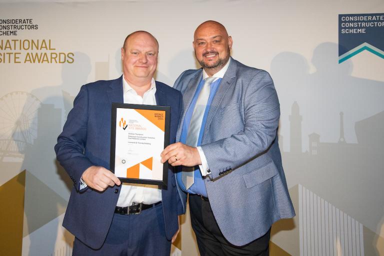 Two people holding an award certificate