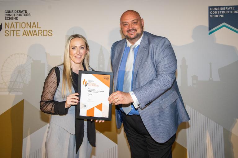 Two people holding an award certificate