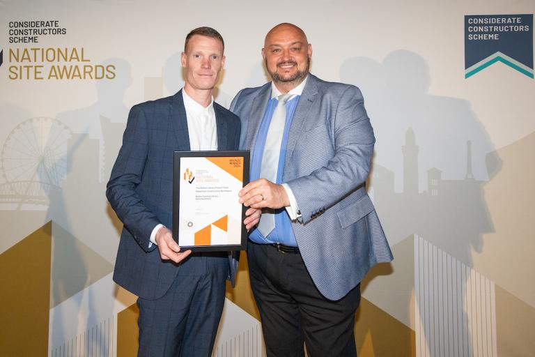 Two people holding an award certificate
