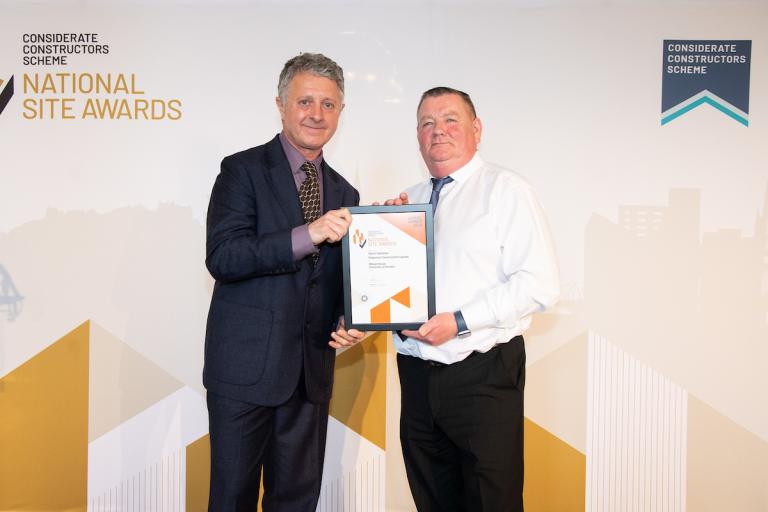 Two people holding an award certificate