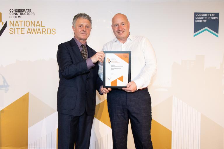 Two people holding an award certificate